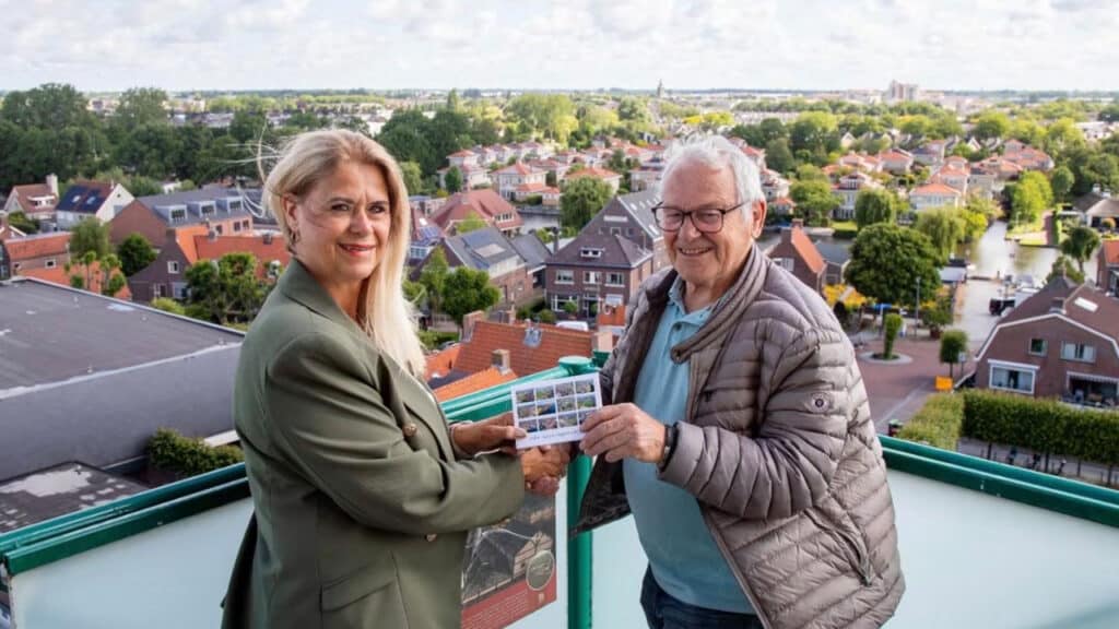 Op de foto neemt wijkraadvoorzitter Jolanda van der Nagel het jubileummapje in ontvangst uit handen van Henk Imthorn, voorzitter van de Vereniging Oud Valkenburg.